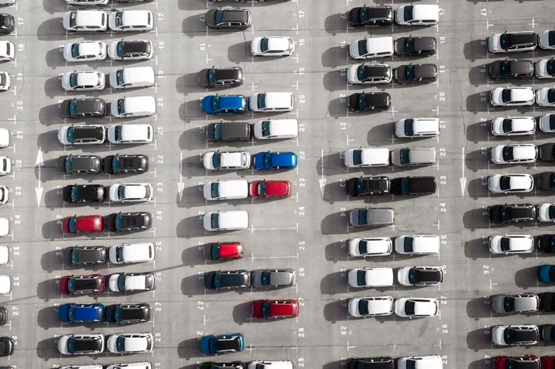 Vogelperspektive auf einen großen Parkplatz bei Gebrauchtwagen Ankauf Elmshorn, der mit Reihen weißer Autos gefüllt ist.